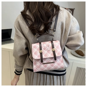 Detail eines rosa karierten Rucksacks mit Ledergriffen und niedlicher Karikaturgrafik