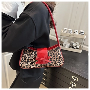 Detailed shot of leopard print shoulder bag with red patent leather strap and bow decoration