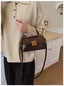 Detail view of dark brown leather handbag with suede flap and gold geometric lock