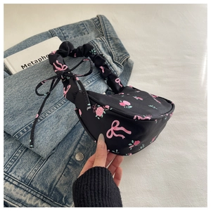 Détail du sac floral noir avec roses roses et poignée froissée sur une veste en jean