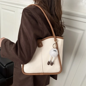 Bolso tote minimalista de cuero blanco roto con ribete marrón y colgante de peluche