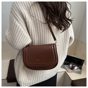 Detail of deep brown crossbody bag with gold Fashion lettering on textured leather