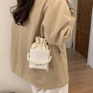 Détail du sac seau blanc avec poignée en perles larges et bandoulière en chaîne dorée