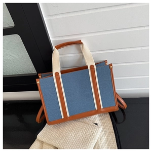 Detail der Denim-Einkaufstasche mit Lederbesatz und breiten Canvas-Griffen zum Tragen