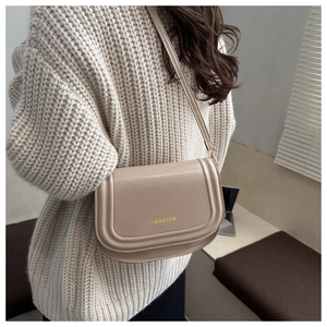 Detailed view of fashionable beige PU leather shoulder bag with golden FASHION logo