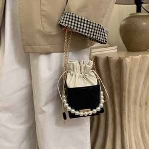 Détail du sac seau avec poignée en perles, cordon en velours et chaîne dorée