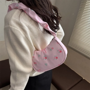 Sac à bandoulière rose à motif floral et roses, porté par un mannequin dans un intérieur