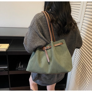 Détail du sac cabas en daim vert foncé avec anses en cuir marron et boucle argentée