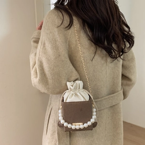 Mini sac seau perle avec chaîne dorée porté par un mannequin dans un style d'automne