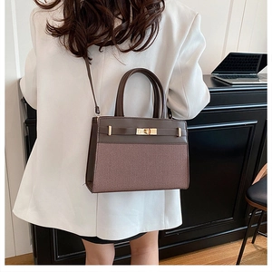 Brown leather and weave texture handbag shown with white blazer on a model
