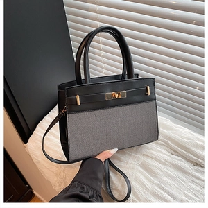 Detailed view of two-tone Kelly bag with gold twist lock and woven texture design