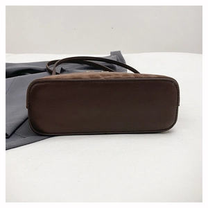 Détail du fond d'un sac en cuir marron foncé avec textures embossées et coutures de qualité