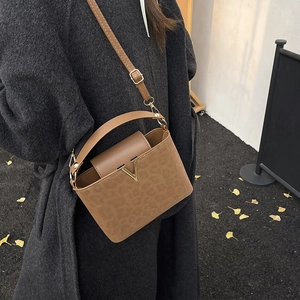 Sac à main marron avec imprimé léopard et boucle en V doré porté par un mannequin