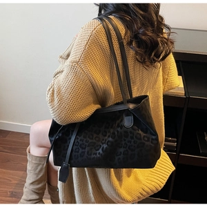 Detail of black leopard print tote bag with leather straps on a knit sweater