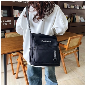 Outdoor shot of the black canvas crossbody bag with adjustable wide shoulder strap detail