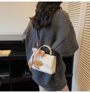 Detail of white mini square bag with patterned silk scarf handle and gold buckle closure