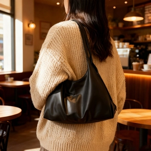 Borsa tote classica in pelle nera opaca abbinata a un maglione beige in un caffè