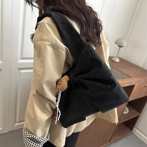 Minimalist black crossbody bag with a large bow design and a brown teddy bear charm