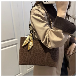 Détail du sac cabas léopard avec texture en daim et accessoire élégant en foulard de soie