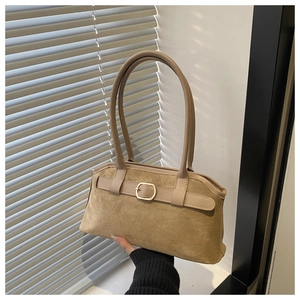 Gros plan d'un sac porté épaule en daim marron avec boucle dorée et lanières en cuir