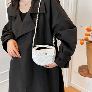 Sac bandoulière matelassé blanc élégant avec fermoir fleur dorée sur manteau noir