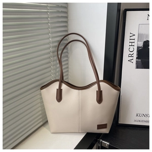 Detailed close-up of lychee grain PU leather texture and brown logo patch on the tote bag
