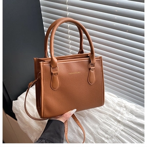 Detail of brown litchi pattern leather tote with gold hardware and fashion text