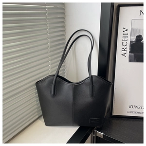 Detail shot of black tote bag featuring lychee texture leather and wavy top design