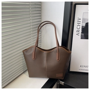 Close-up of brown pebbled leather tote bag with fashion label by a sunny window