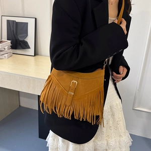 Brown suede crossbody bag with fringe details and metal buckle shown on a model