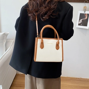 Minimalist cream and brown contrast shoulder bag with top handles shown in home setting