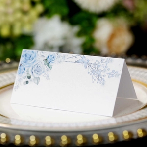 Elegant white place card with blue roses and butterfly on a gold rimmed dinner plate