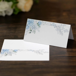 Elegant white pearlescent wedding place cards with blue rose and butterfly motifs