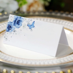 Elegant white wedding place card with blue rose and butterfly design on a gold plate