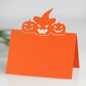 Halloween pumpkin place cards made of laser-cut orange paper for party table settings