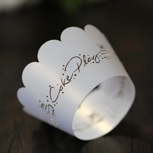 Elegant white scalloped hollow cake wrapper with artistic Cake Playing print on wood