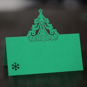 Elegant green Christmas place card featuring hollow tree design and snowflake print