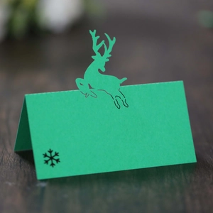 Green Christmas reindeer place card with laser-cut deer and snowflake on wooden table