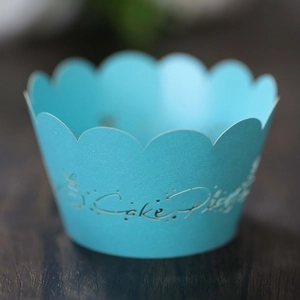 Elegant light blue hollow-out cupcake wrapper with Cake Display text on wooden background
