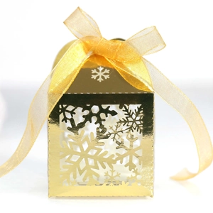 Boîte à bonbons dorée en forme de maison avec flocons évidés et ruban satiné