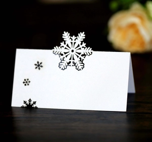 Elegant white foldable Christmas place card featuring laser-cut snowflake details for tables