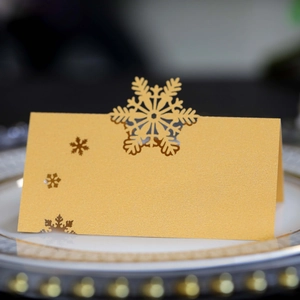 Golden snowflake laser-cut place card on white dinner plate for holiday table decor