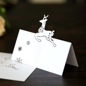 Laser cut white reindeer and snowflake place cards for elegant Christmas table setting