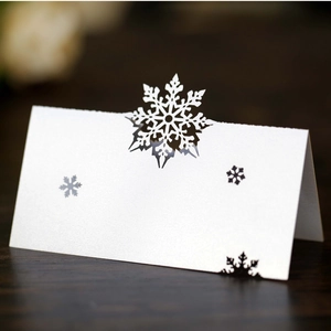 Macro shot of laser-cut white snowflake place card on textured dark wood surface