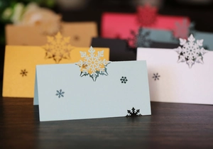 Macro detail of laser-cut snowflake place cards in multiple colors on a wood surface