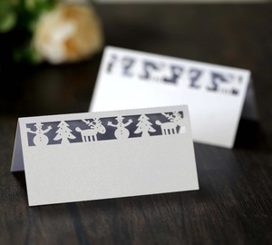 White laser-cut Christmas place cards featuring snowflake and reindeer patterns