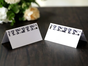Laser-cut Christmas place cards with white snowman and reindeer designs on wood