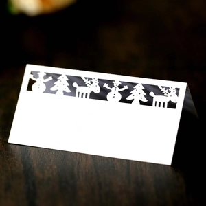 Laser-cut Christmas place card with white reindeer snowman tree silhouettes on wood