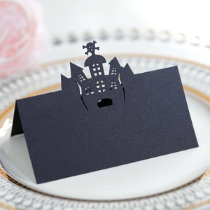 Laser-cut black Halloween place card with castle and skull silhouette on a porcelain plate