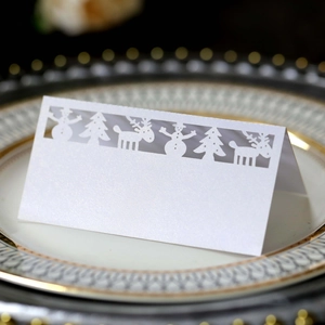 Laser-cut Christmas place card with snowflake and reindeer design on white pearlescent paper